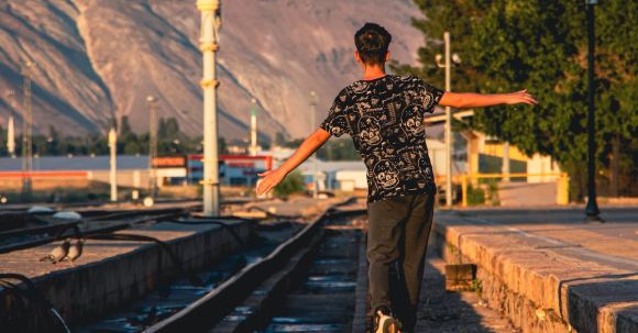 Balance. - Teenage Boy Walking on Railway Tracks