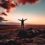 Victory - person standing on rock raising both hands
