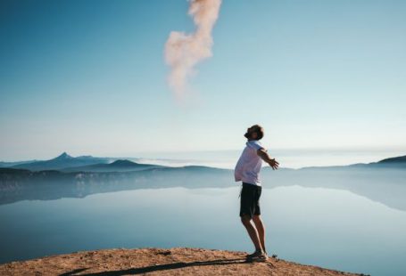 Happiness - man standing on sand while spreading arms beside calm body of water
