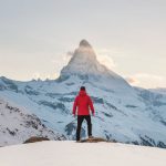 Success - person in red hoodie standing on snowy mountain during daytime