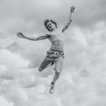 Taking Action. - grayscale photo of person jumping overlooking clouds
