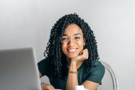 Positive Transformations - Happy ethnic woman sitting at table with laptop
