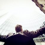 Success - low-angle photography of man in the middle of buidligns