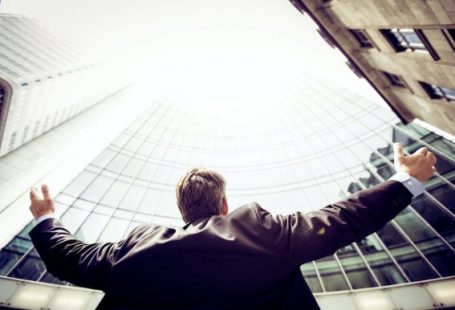 Success - low-angle photography of man in the middle of buidligns