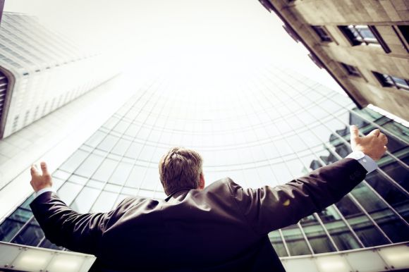 Success - low-angle photography of man in the middle of buidligns